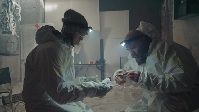 Two caucasian scientists in hazmat suits examine nuclear sample inside abandoned frostbound house, headlamps slicing through cold dust, gloved hands handling vial and instruments, improvised field
