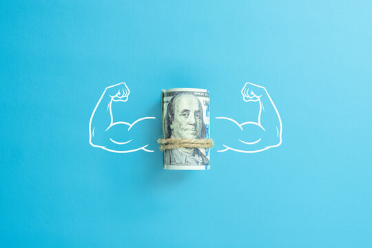 The concept of a strong world currency. Muscle hands with a bunch of us dollars money.
