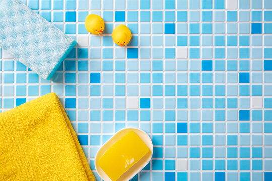 Children's bath accessories and copy space for text on blue tiles background.