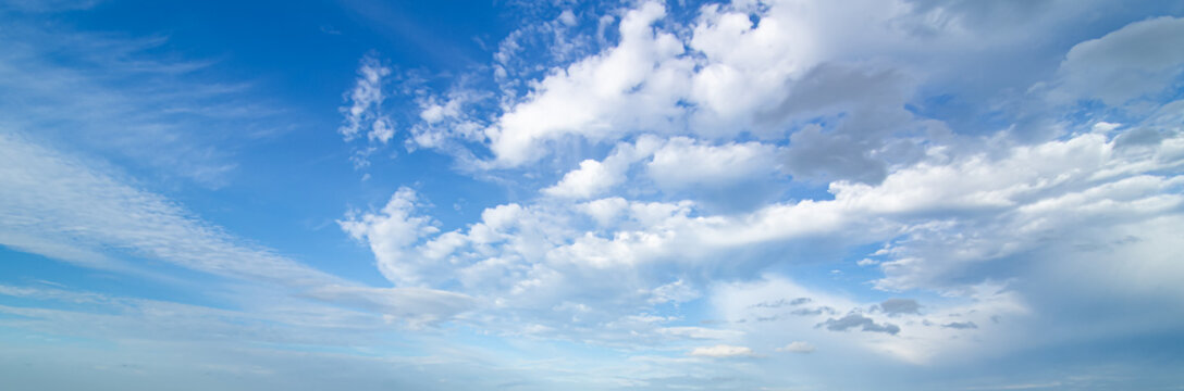 Vibrant blue sky panorama with fluffy white clouds and bright sunlight.