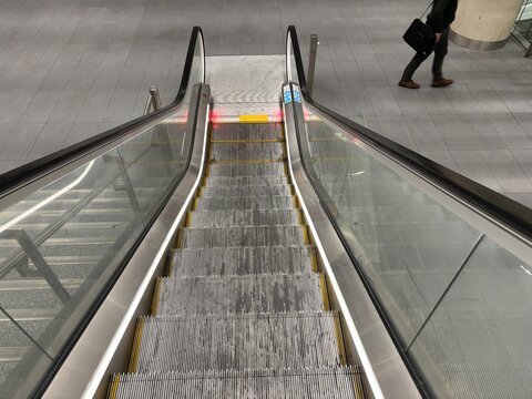 Escalator stairs descending with a person walking in the background  