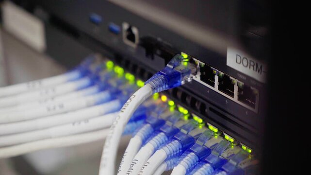 A digital network hub connects patch cables and panels to an ethernet switch for high-speed data communication between server equipment and laptop computers in a modern business technology studio