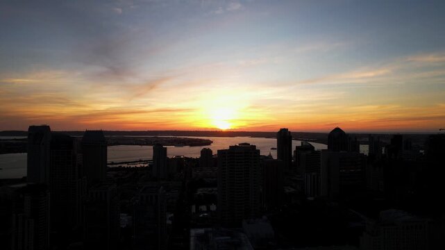 Second take of drone flying backward at sunset with camera tilting down over downtown San Diego buildings.
