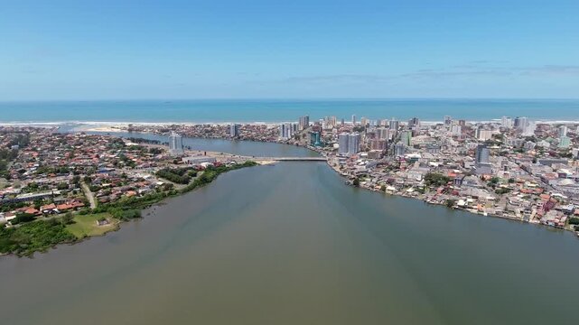 Aerial establishing shot flying toward the bridge linking Imbe and Tramandai with the coast and ocean in southern Brazil.