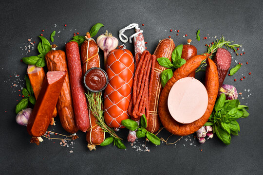 Assortment of salami and snacks. Sausage Fouet, sausages, salami, paperoni. On a black wooden background. Top view. Free space for your text.