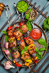Obraz na płótnie Canvas Kebabs - grilled meat skewers, shish kebab with vegetables on a plate. On a concrete old table. Top view.