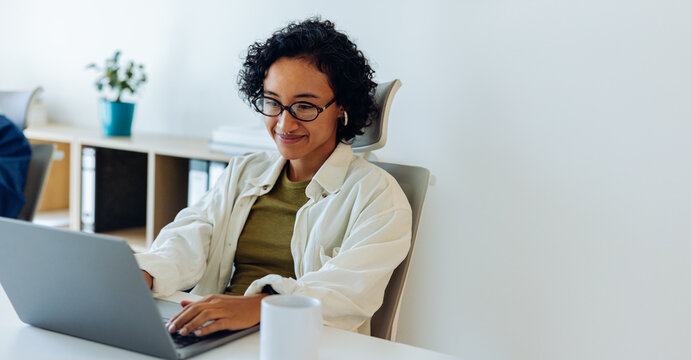Woman works on laptop at desk in office