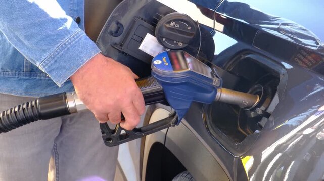 Man Refueling Car at Gas Station During Rising Fuel Costs and Energy Crisis, Close-Up of Hand Holding Nozzle at Pump, Everyday Transportation Expense Concept.