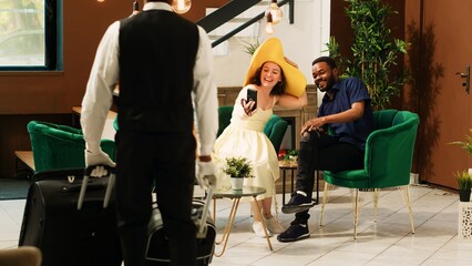 Guests using videocall meeting in hotel reception lobby, talking to someone on online...