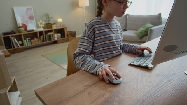Zoom out shot of young Caucasian girl playing computer games while her brother using joystick in background in living room