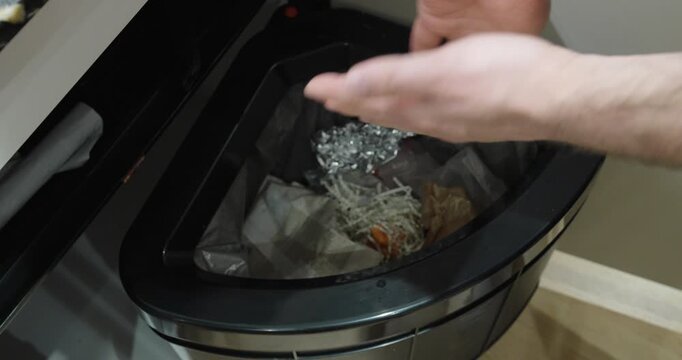 Hand throwing pieces of a destroyed credit card into a trash bin. Concept of data protection, financial security, and safe disposal of sensitive information.