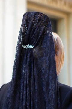 Faceless image of traditional use of the mantilla by a godmother in a formal or religious ceremony in Spain.