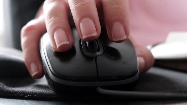 female hand moving optical computer mouse on pad at desk closeup, person browsing internet slow motion.