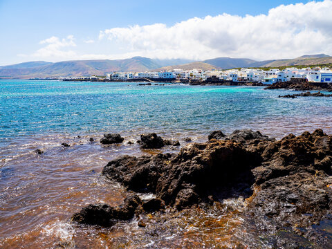 coastal view of punta mujeres lanzarote with volcanic rocks turquoise atlantic water and white village houses along the shoreline