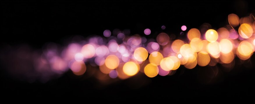 Colored bokeh lights forming diagonal trail on black background