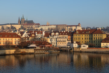 Obraz premium scenic view of Prague Castle and Charles Bridge glowing in golden light over the Vltava River
