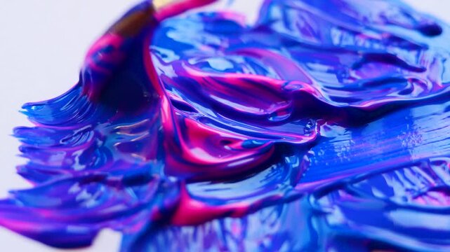Close-up of brush strokes blending pink and blue acrylic paint, smooth texture and vibrant colors in motion. Perfect for artistic backgrounds, painting tutorials and creative projects