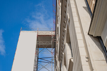 Naklejka premium Metal scaffolding erected against the side of a historic stone building for renovation.