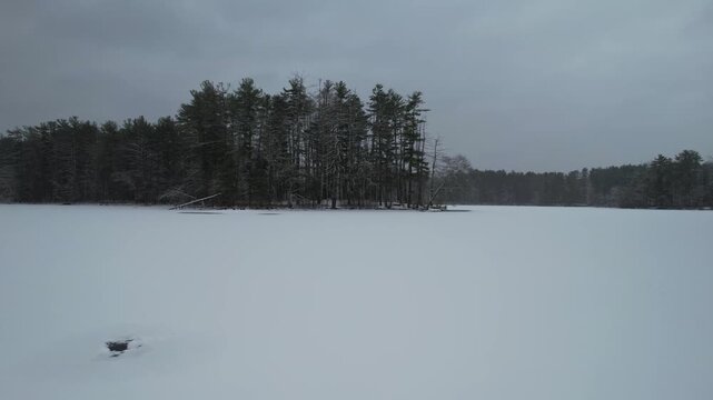 Fast aerial over frozen lake and snow covered landscape, Harold Parker State Forest, Massachusetts, USA