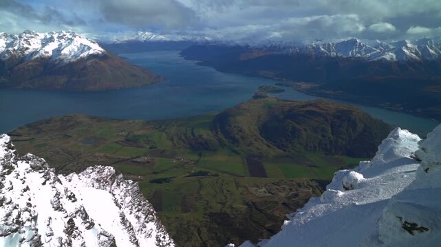 Look out The Remarkables Ski Resort winter jagged snowy covered peaks Rock face New Zealand Lake Wakatipu Queenstown Frankton lush green valley morning sunny blue sky clouds landscape pan left