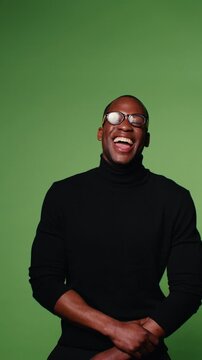 Happy man in black turtleneck and glasses laughs on green screen background. Perfect for commercials, presentations, and more.