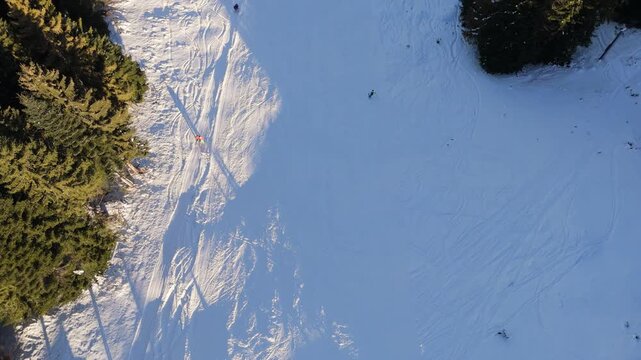 Aerial View Zooming In on Skier Carving Down Sunny Mountain Slope
