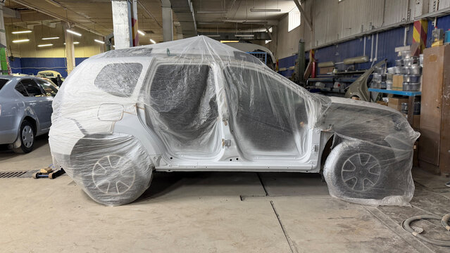 Car covered with plastic in auto repair workshop