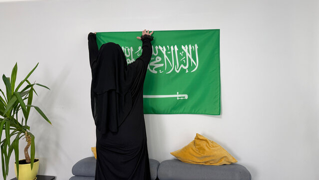 Saudi Arabia woman adjusting national flag at home