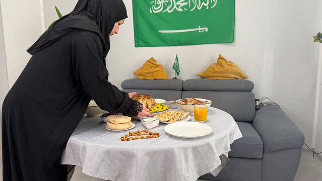 Saudi Arabia woman arranging Iftar table with traditional dishes