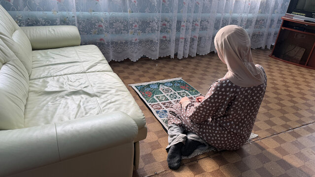 Saudi Arabia woman sitting on prayer rug at home during Ramadan