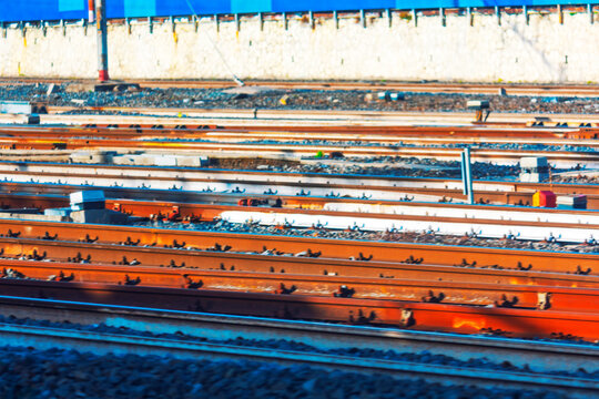 Multiple railway tracks run parallel across, rusted steel surfaces. Train tracks stretching across gravel rail yard. Industrial view of rusty railroad tracks with concrete ties and gravel ballast