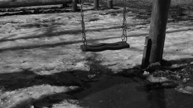 Park and swingings. Simple shot captures retro atmosphere, passage of time, subtle melancholy, vintage aesthetics, nostalgia. Deep long shadows, monochrome colors for strong visual storytelling