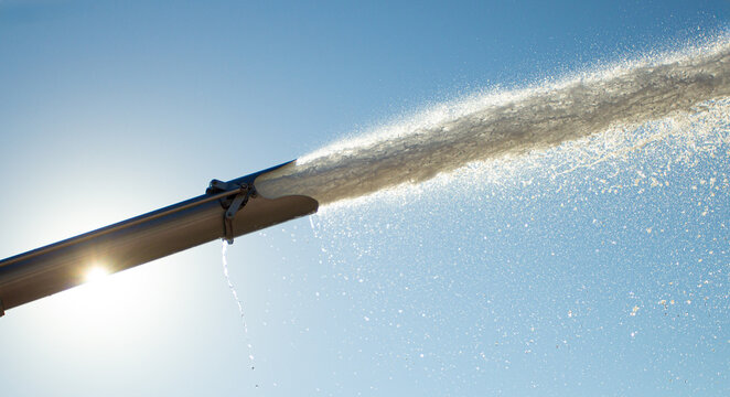 Water gushing from irrigation pipe under clear sky