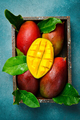 Naklejka premium Fresh tropical fruits ripe mango with leaves in a wooden box. Top view. Fresh fruits.