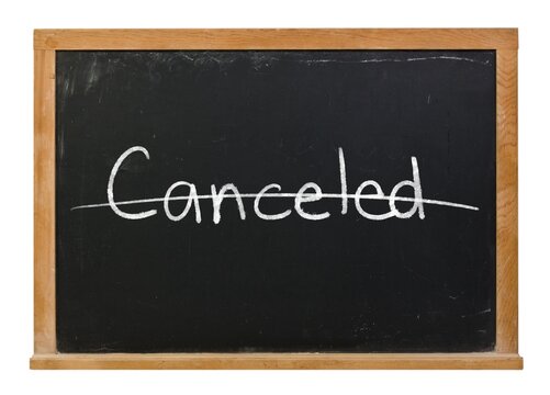 Canceled written in white chalk on a black chalkboard isolated in a wooden frame on white