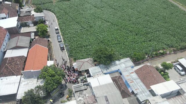 Aerial view of a traditional wedding procession walking through a rural Indonesian neighborhood.