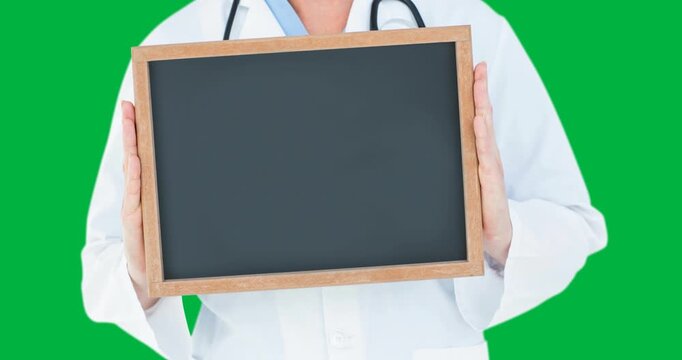 Mid section of a doctor holding blank blackboard ith with copy space against black background
