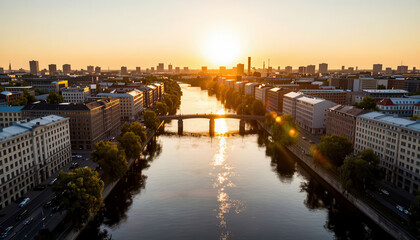 Fototapeta premium a river flowing through a cityscape at sunset. Buildings line the riverbank, while sunlight reflects off the water, creating a serene atmosphere.