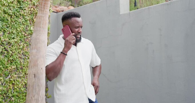 Receiving call, adult African American man by vine wall, holding red phone, reacting, ending call