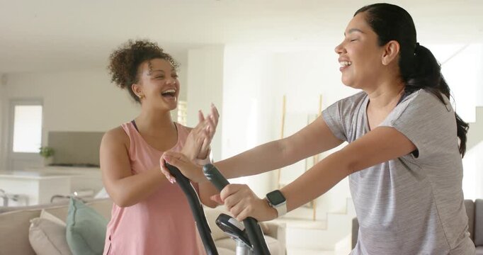 Exerciser pedaling elliptical, supporter initiating applause and high-fives, boosting fitness
