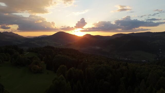 Aerial forward motion over mountain landscape during golden sunrise or sunset