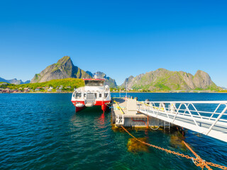 Harbor pier in a village in Lofoten, Norway. Scenic summer arctic landscape with mountains, fjord, and ferry. Concept of travel, vacation, and nautical tourism in Scandinavia. © biletskiyevgeniy