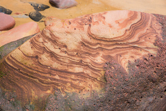 red sandstone with visible sediment layers, at sandy beach