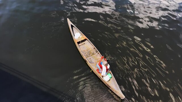Local woman rowing a small wooden boat along a tranquil backwaters of  Kerala	