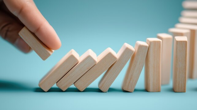business risk control and crisis prevention background with copy space, hand stopping domino effect chain reaction of wooden blocks showing strategy, protection and stability management