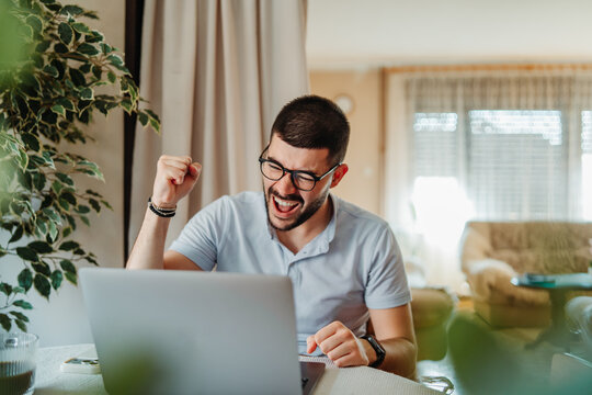 Happy man celebrating success working on laptop