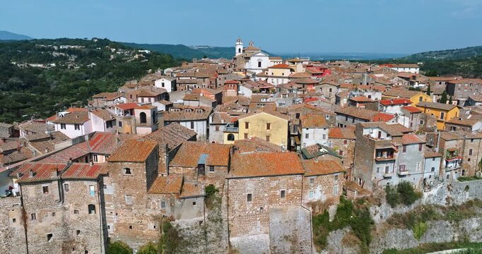 Cinematic aerial view of the medieval architecture of Orte. Focus on the red-tiled townscape and the contrast between ancient stone and summer greenery. Italian rural charm and travel inspiration