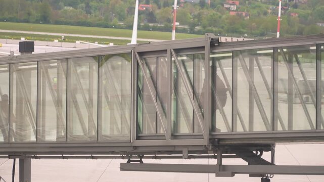 Contemporary glass jet bridge at airport terminal, designed for efficient passenger boarding and disembarking. Urban travel infrastructure with panoramic windows and sleek architecture