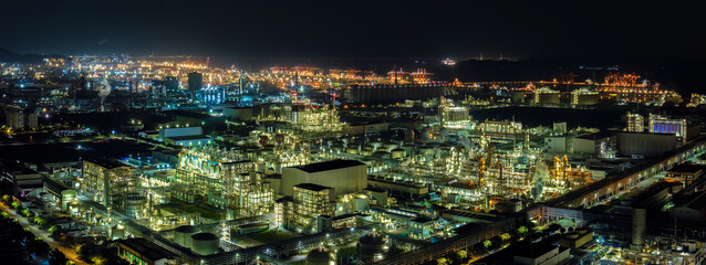 Obraz premium Night aerial view of a brightly illuminated chemical plant and oil refinery complex showing modern industrial infrastructure.