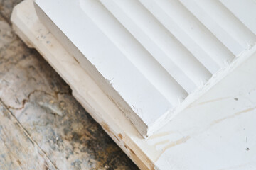 Close up of white moulded plaster decorative trim with stepped profile on wooden surface for interior design and construction detail. Manufacture and construction of moulds  © dannyburn